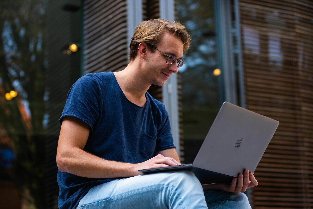 Male college student doing ACT test prep with an online tutor virtually over his laptop